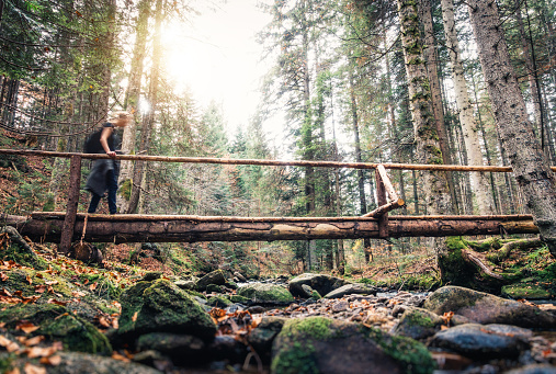 Woman crossing the bridge in the forest. Low angle view.