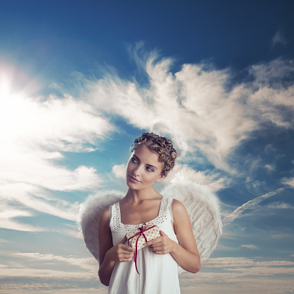 Angel holding wrapped gifts with sky and clouds in the background.