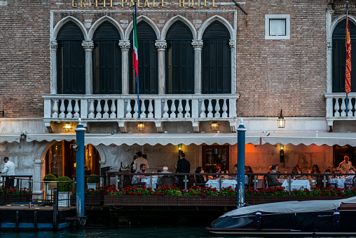 Venice, Italy - June 11, 2014: Venetian dining, seen from the academica bridge, see people sitting in a small restaurant oudside and enjoing the night