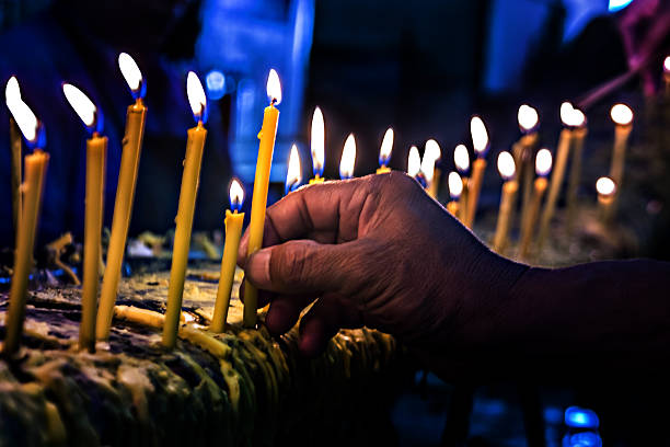 istock old hand ligthing candle in temple at dark 497123620