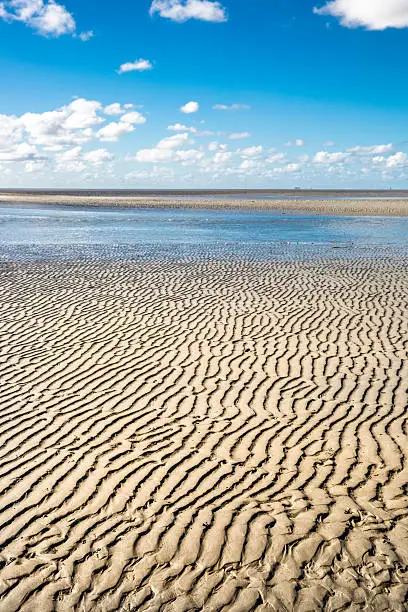 Maritime landscape with blue sky white clouds and pattern in the sand, Waddenzee - Wadden Sea, Friesland, The Netherlands