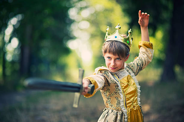 Little girl practicing swordplay - princess that doesnt need saving Little 9 year old princess practicing sword play in forest. The girl is wearing princess dress and crown and is wielding a sword with obvious proficiency. sword photos stock pictures, royalty-free photos & images