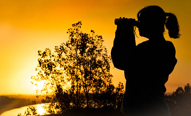 istock Young woman looking through binoculars in silhouette 497125456