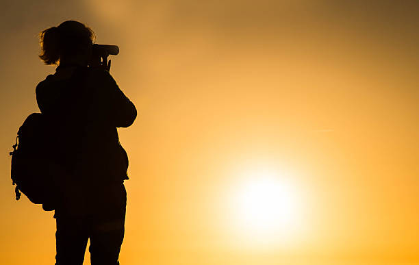 istock Young woman looking through binoculars in silhouette 497125498