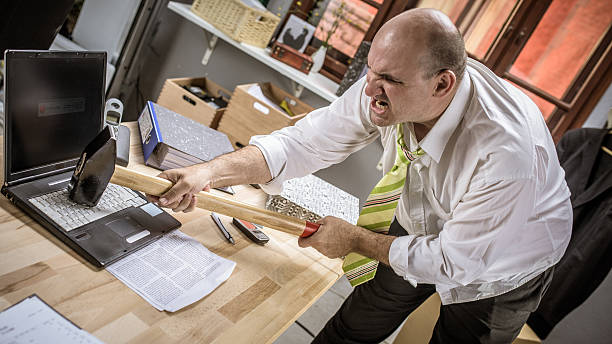 istock Angry office worker destroying his laptop with a sledgehammer 497125580