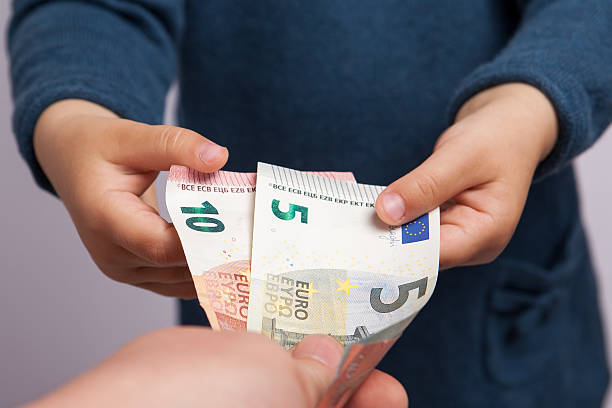 Small child hand takes five and ten euros banknotes Small child hand takes five and ten euros banknotes from adult hand 10 11 years photos stock pictures, royalty-free photos & images