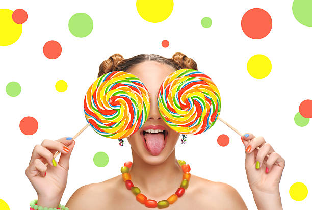 Lollipops, candy smile on, are scattered around the colorful jelly beans on a white background.. Top view, flat