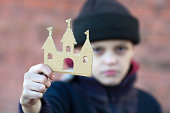 yong homeless boy holds a cardboard castle