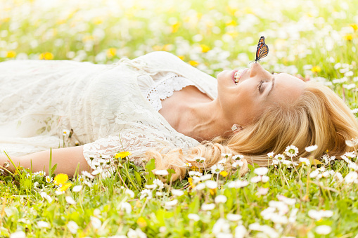 Butterfly on woman's nose, woman lying down on the grass.