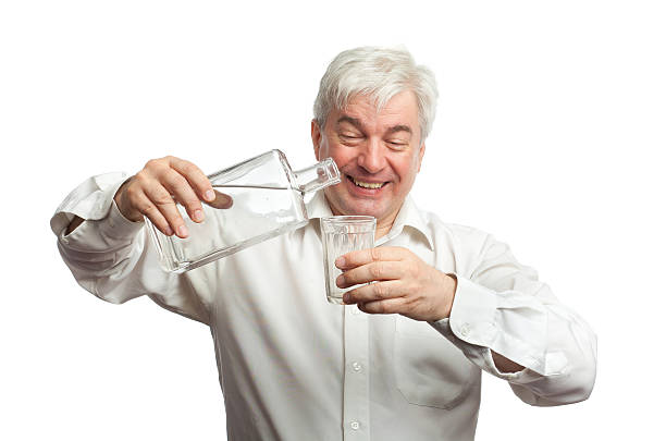 istock Man, pouring vodka into the glass against a white background. 497128285