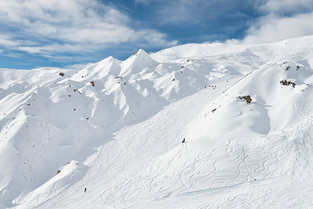 einige menschen skifahren im alpine mountain resort an einem sonnigen tag - ski trace stock-fotos und bilder