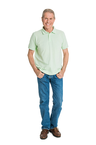 Full length portrait of confident senior man with hands in pockets standing against white background