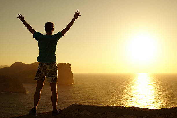 istock Silhouette of a young man with hands raised 497129960