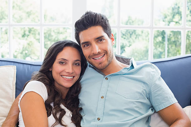 istock Attractive couple on sofa smile at the camera 497131633