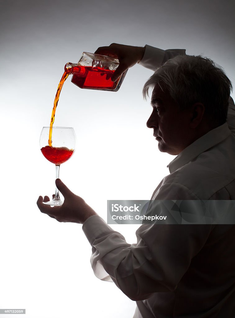 Man, pouring the wine into the glass Man, pouring the wine into the glass on a gray background. Addiction Stock Photo
