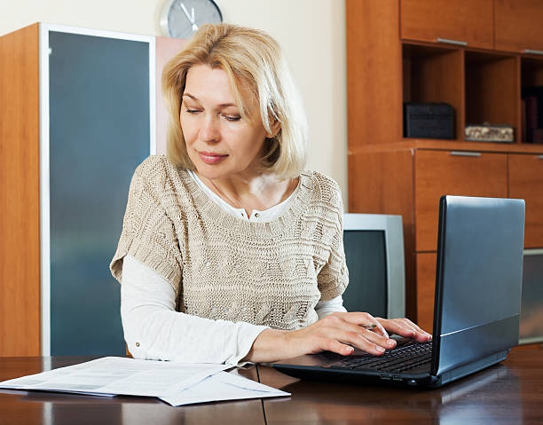 istock woman with laptop and financial documents at home 497145018