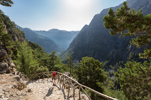 A woman on her way down to the entrance of Samaria Gorge, Crete. The gorge is in southwest Crete in the regional unit of Chania and a major tourist attraction of the island. It was created by a small river running between the White Mountains and Mt. Volakias. The gorge is 16 km long, starting at an altitude of 1,250 m (4100 ft.)at the northern entrance, and ending at the shores of the Libyan Sea in Agia Roumeli.