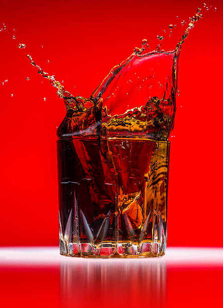 istock Glass with whiskey splash on red background 497148701
