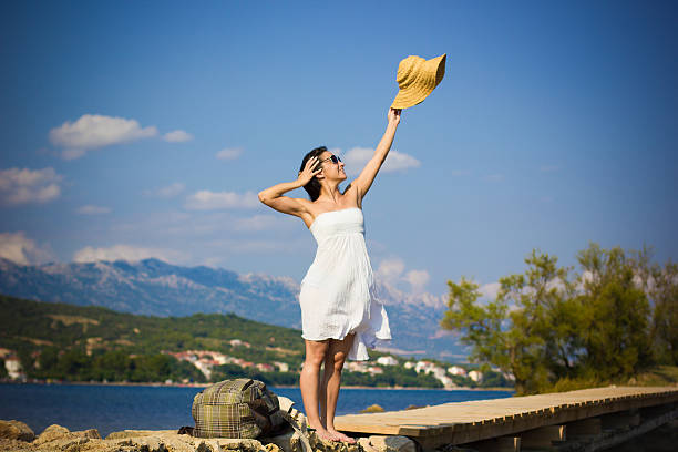 Beautiful young woman waving by the sea