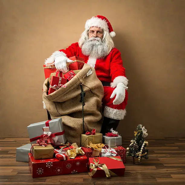 Photo of santa claus with many gifts in his bag