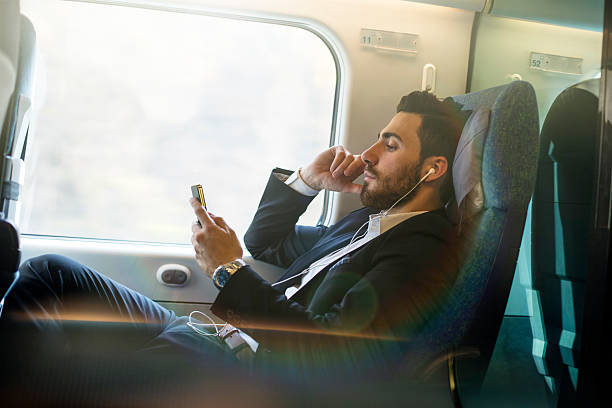 istock bussinesman seating on a train  beside  window  and using phone 497153576