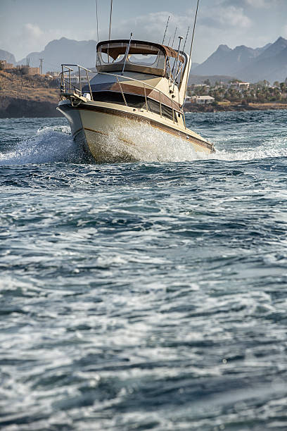 Deep Sea Fishing Boat Small ocean going vessel at high speed near rocks on a fishing trip yacht rock music stock pictures, royalty-free photos & images