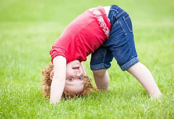 Little girl upside down on the grass.