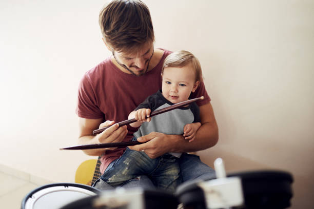 Making a future rockstar A handsome young father teaching his young son to drum fashionable dad stock pictures, royalty-free photos & images