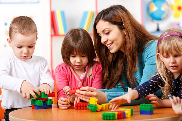 istock Nursery teacher and preschoolers playing with building blocks 497158923