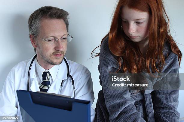 Hospital Doctor Showing Notes To Girl Patient On His Clipboard Stock Photo - Download Image Now