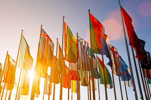 colorido mundo international flags saludar con la mano en el cielo al atardecer - global politics fotografías e imágenes de stock