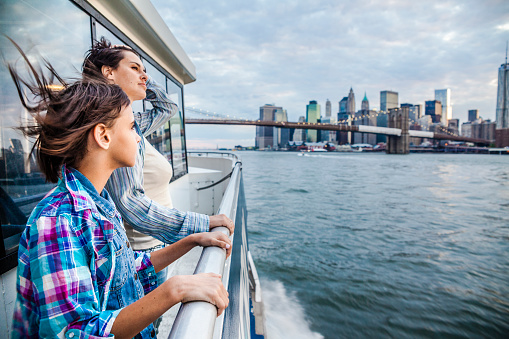 Mother and daughter at ferry at Hudson River, in front of far Manhattan's skyline 