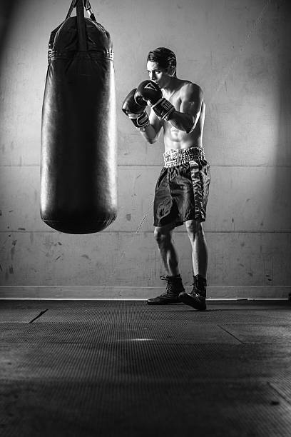 istock Hispanic Man Hitting a Punching Bag in Black and White 497177924