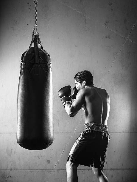istock Hispanic Man Hitting a Punching Bag in Black and White 497178408