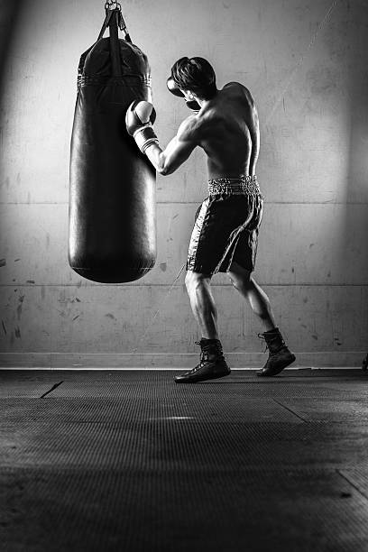 istock Hispanic Man Hitting a Punching Bag in Black and White 497179388