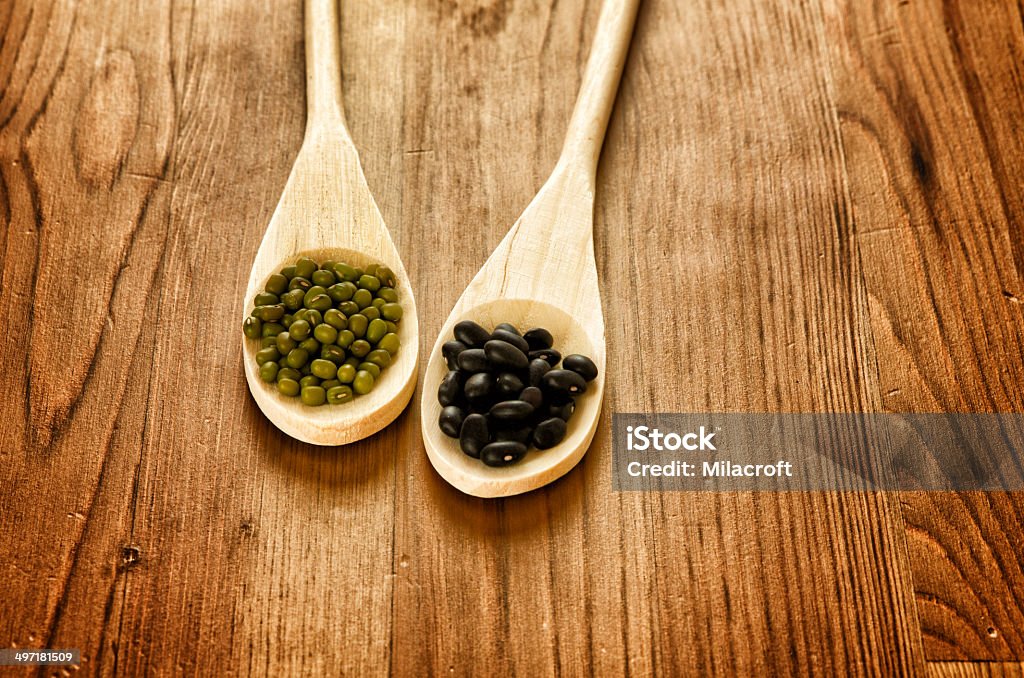 Soybeans and black beans in wooden spoons Green soybeans and mexican black beans on wooden background, biologic agriculture Agriculture Stock Photo