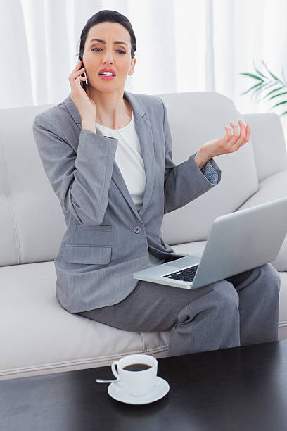 istock Serious businesswoman calling with her mobile phone and using laptop 497185921