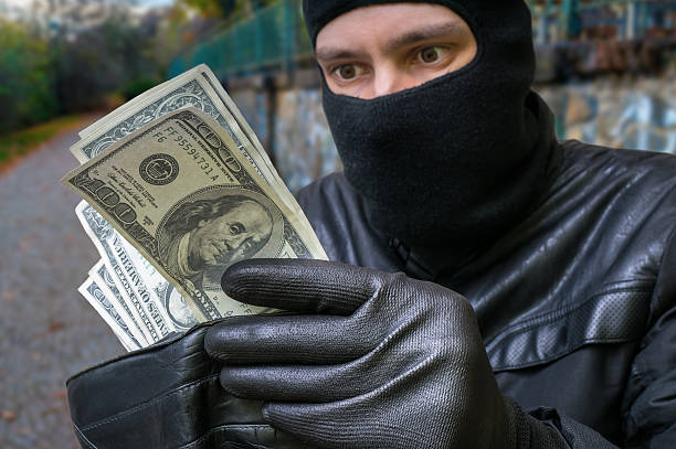 istock Stealing concept. Masked thief is counting money in stolen walle 497186328