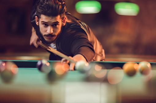 Young man playing snooker in a pub.