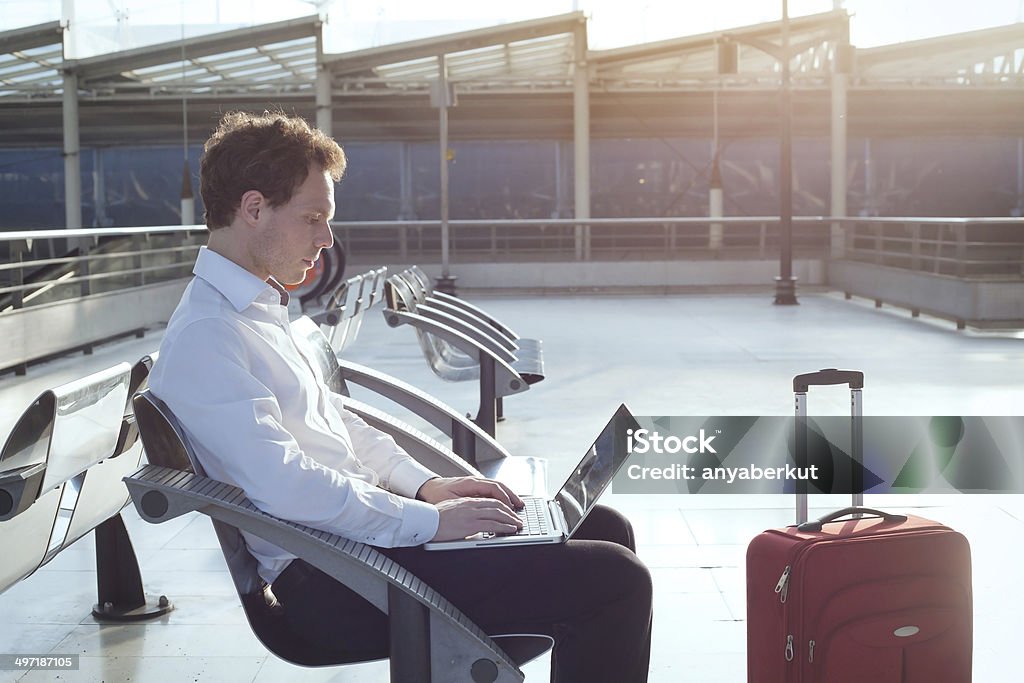Businessman sitting at airport with laptop using internet in the airport terminal Working Stock Photo