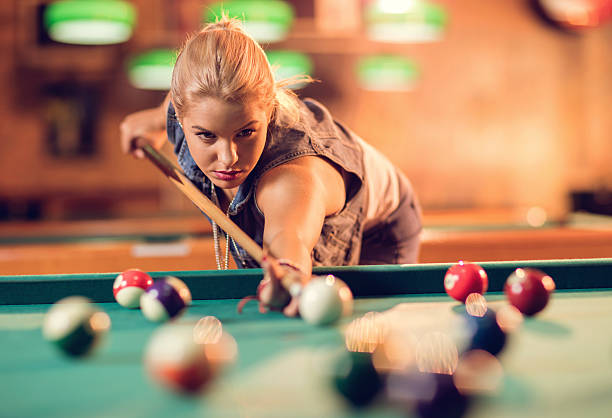 Young beautiful woman playing billiard in a pool hall.