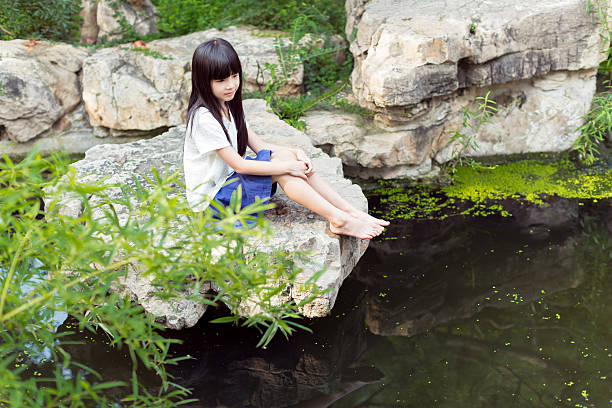 chinese sweet and innocent little girl, in the park's pond barefoot playing in the water