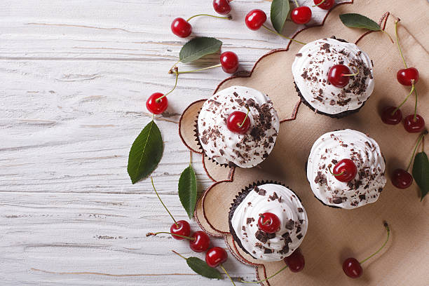 istock Chocolate cupcakes with cream and cherry horizontal top view 497189154
