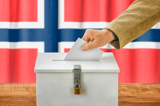 Man putting a ballot into a voting box - Norway