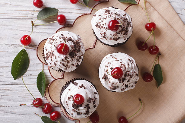 Chocolate cupcakes with cream and cherry closeup horizontal top