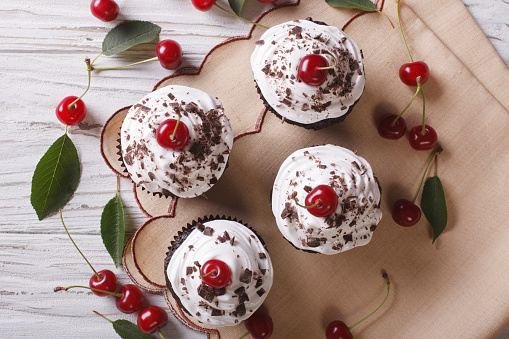 Chocolate cupcakes with cream and fresh cherry Black Forest close up on the table. horizontal top view