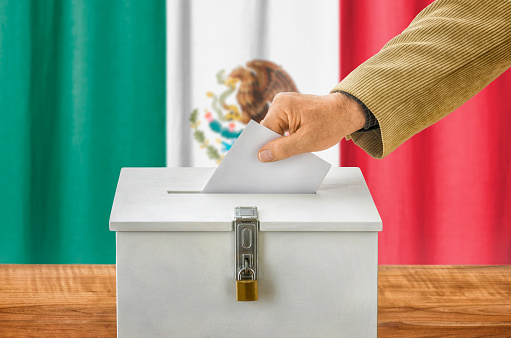 Man putting a ballot into a voting box - Mexico