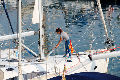 Barcelona, Spain - September 25, 2014: Spanish woman washes a yacht moored in Puerto Olimpico in Barcelona