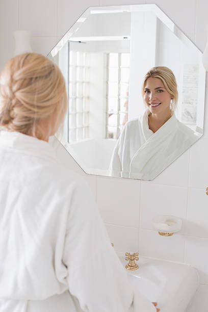 istock Smiling woman looking at herself in bathroom mirror 497198531