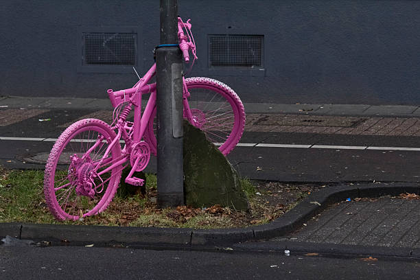Bicycle pink in front of dark wall on green stripes